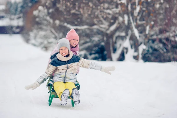 Adorable little happy girls sledding in winter snowy day. — Stock Photo, Image