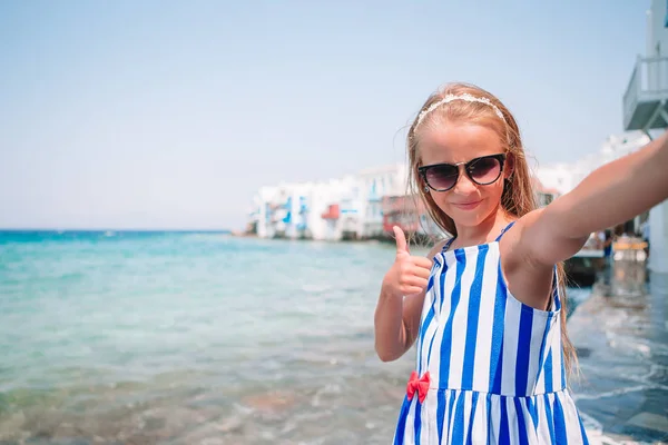Lilla bedårande flicka med självporträtt i Mykonos gator under sommaren grekiska semester — Stockfoto