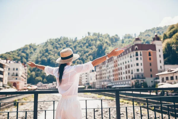 Ευτυχισμένος κορίτσι στο καπέλο για το ανάχωμα του ένα ποτάμι βουνό σε μια ευρωπαϊκή πόλη. — Φωτογραφία Αρχείου