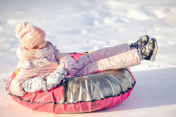 हिवाळा बर्फ दिवस मध्ये मोहक थोडे आनंदी मुलगी स्लेडिंग . — स्टॉक फोटो, इमेज