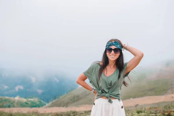 Vacker glad ung kvinna i bergen i bakgrunden av dimma — Stockfoto