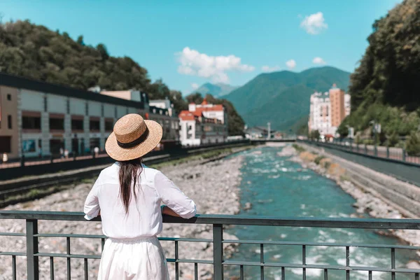 Menina feliz no chapéu no dique de um rio de montanha em uma cidade europeia . — Fotografia de Stock