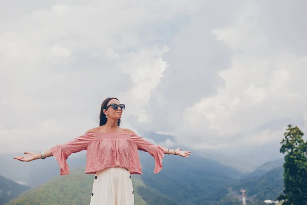 Mulher jovem feliz bonita em montanhas no fundo do nevoeiro — Fotografia de Stock