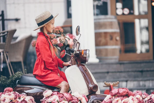 Entzückendes kleines Mädchen mit Hut auf dem Moped im Freien — Stockfoto