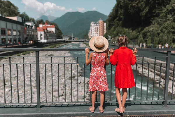 Back view of girls on the embankment of a mountain river in a European city. — Stock Photo, Image