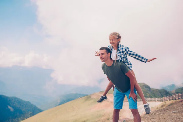 Beautiful little girl and young father in mountains in the background of fog — Stock Photo, Image