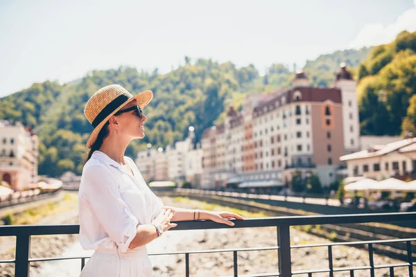 Gelukkig meisje bij hat aan de kade van een rivier berg in een Europese stad. — Stockfoto