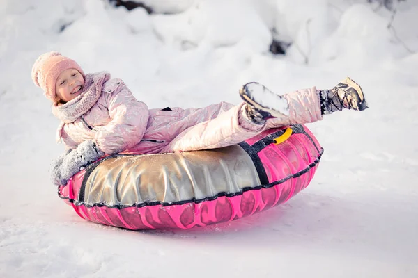 Schattig klein gelukkig meisje sleeën in de winter besneeuwde dag. — Stockfoto