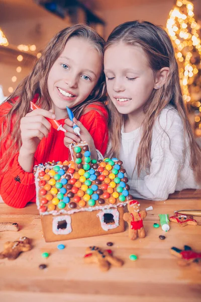 Entzückende Kleine Mädchen Dekorieren Lebkuchenhaus Mit Glasur Hintergrund Von Lichtern — Stockfoto