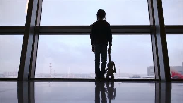 Menina no aeroporto perto de uma grande janela enquanto espera pelo embarque — Vídeo de Stock