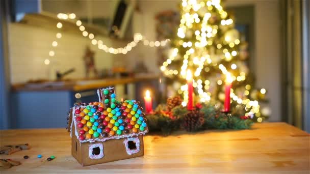 Casa de fadas de gengibre em um fundo de árvore de Natal brilhante com grinalda — Vídeo de Stock