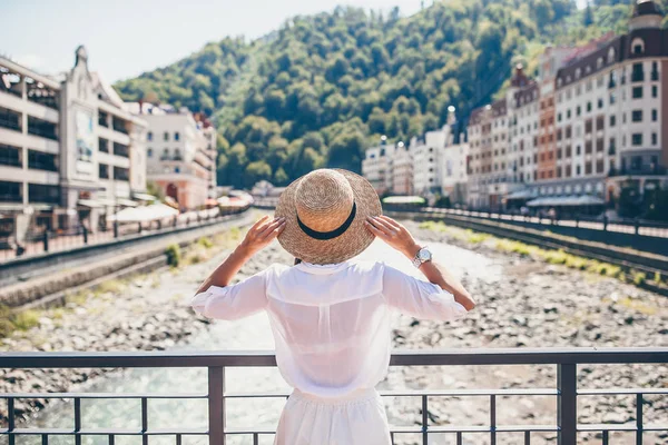 Menina feliz no chapéu no dique de um rio de montanha em uma cidade europeia . — Fotografia de Stock