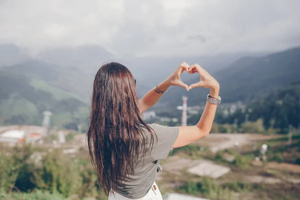 Mulher jovem feliz bonita em montanhas no fundo do nevoeiro — Fotografia de Stock