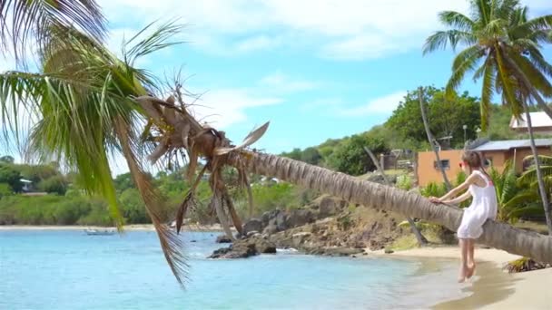 Adorable petite fille assise sur un palmier pendant les vacances d'été sur une plage blanche — Video