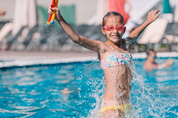 Красивая маленькая девочка развлекается у открытого бассейна — стоковое фото