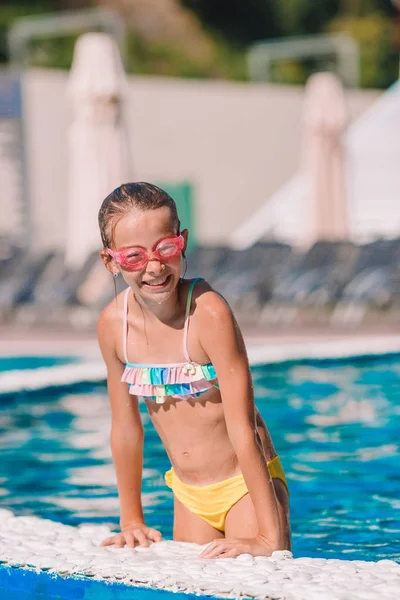 Красивая маленькая девочка развлекается у открытого бассейна — стоковое фото