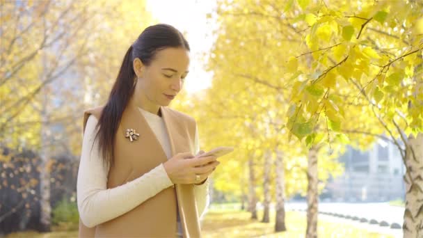 Fall concept - beautiful woman drinking coffee in autumn park under fall foliage — Stock Video