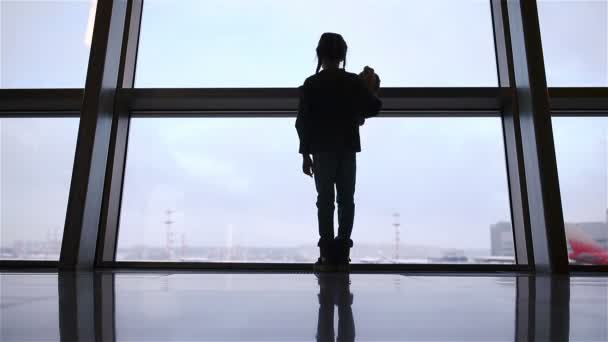 Kleines Mädchen am Flughafen in der Nähe eines großen Fensters, während es auf das Boarding wartet — Stockvideo