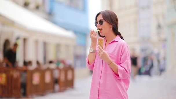 Jonge vrouwelijke model eten ijs kegel buiten. Zomer concept - woamn met zoete ijs op warme dag — Stockvideo