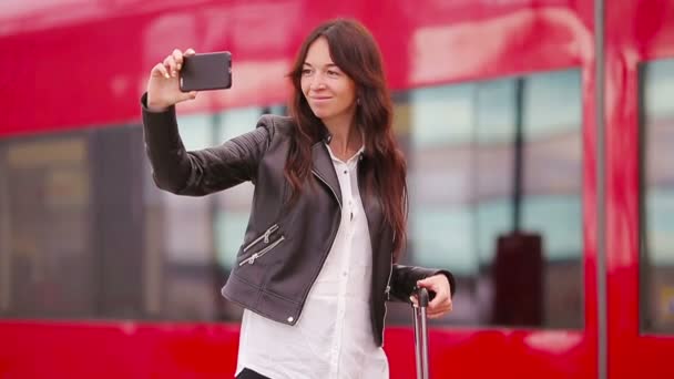 Ung kvinna med bagage tar selfie på en tågstation. Caucasiam turist väntar hennes expresståg medan hon reser. — Stockvideo