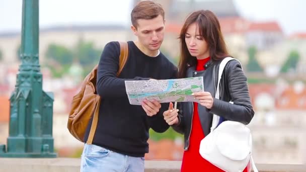 Mladý turistický pár cestující na dovolenou v Evropě se šťastně usmívá. Kavkazská rodina s mapou města při hledání zajímavostí — Stock video
