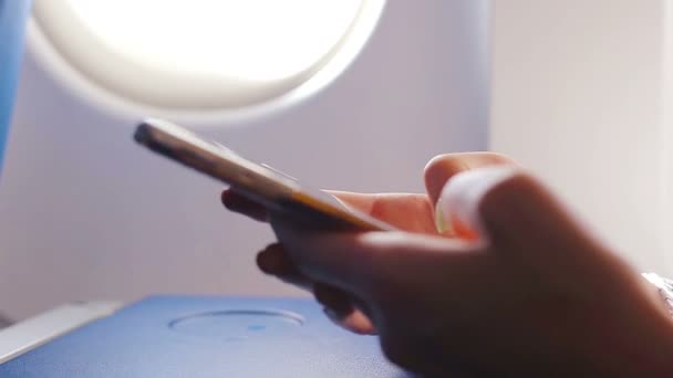 Kobieta wiadomość SMS-y na jej telefon komórkowy. Zbliżenie wyświetlania wewnątrz samolotu tło okna. — Wideo stockowe