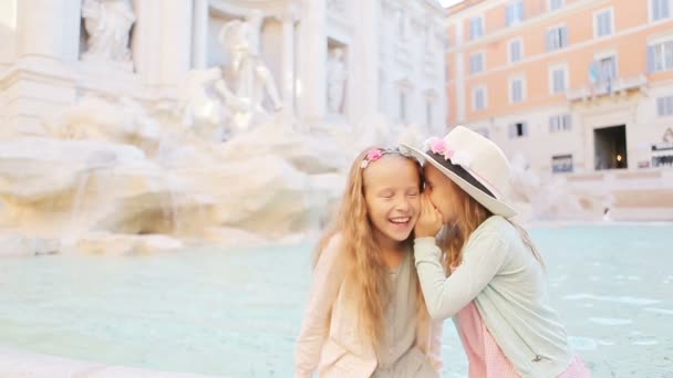 로마 트레비 분수의 가장자리에 앉아 중얼거리는 사랑 스러운 어린 소녀들. 행복 한 아이들은 이탈리아에서 유럽 여행을 즐긴다 — 비디오