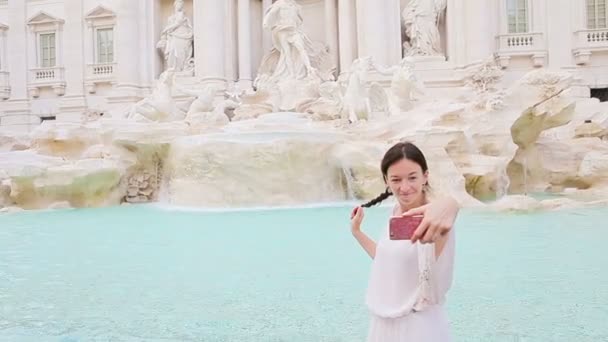 Молодая женщина со смартфоном делает селфи на открытом воздухе в европейском городе недалеко от знаменитого фонтана Треви — стоковое видео