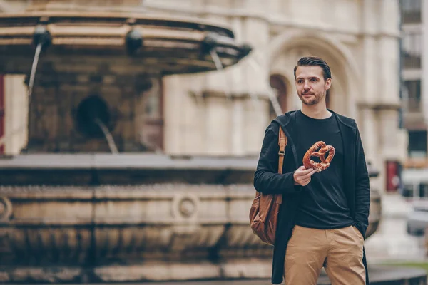 Mooie jongeman met pretzel en ontspannen in het park — Stockfoto