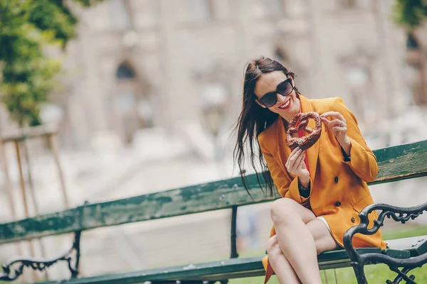 Hermosa mujer joven sosteniendo pretzel y relajarse en el parque —  Fotos de Stock
