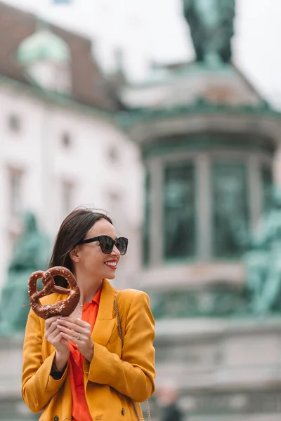 Hermosa mujer joven sosteniendo pretzel y relajarse en el parque — Foto de Stock