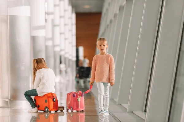 Entzückende kleine Mädchen haben Spaß am Flughafen, wenn sie auf einem Koffer sitzen und auf das Boarding warten — Stockfoto