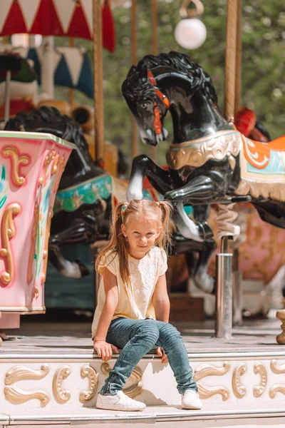 Adorable little girl near the carousel outdoors — Stock Photo, Image