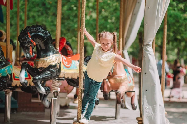 Adorable little girl near the carousel outdoors — Stock Photo, Image