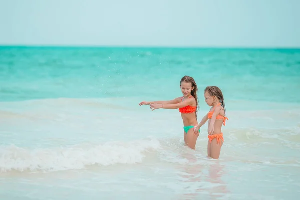 Le bambine si divertono sulla spiaggia tropicale giocando insieme in acque poco profonde — Foto Stock