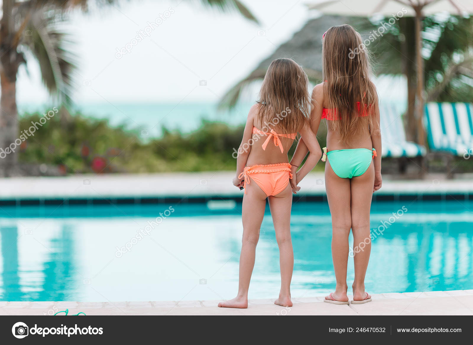 Adorable little girls having fun in outdoor swimming pool on
