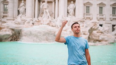 Genç adamın elinde jetonlu Fontana di Trevi Çeşmesi yanında