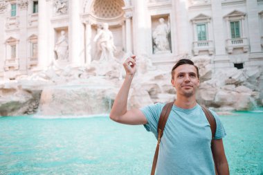 Genç adamın elinde jetonlu Fontana di Trevi Çeşmesi yanında