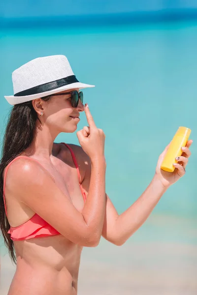 Mujer joven aplicar crema en la nariz en la playa —  Fotos de Stock