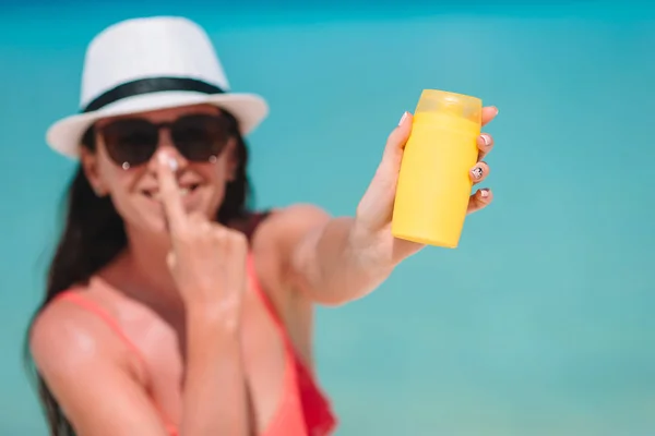 Giovane donna applicare la crema sul naso in spiaggia — Foto Stock