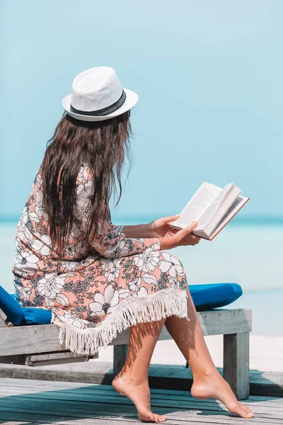 热带马尔代夫海滩期间阅读书籍的年轻妇女 — 图库照片