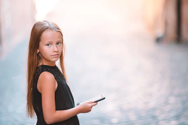 Adorable niña con teléfono celular en la ciudad italiana durante las vacaciones de verano —  Fotos de Stock