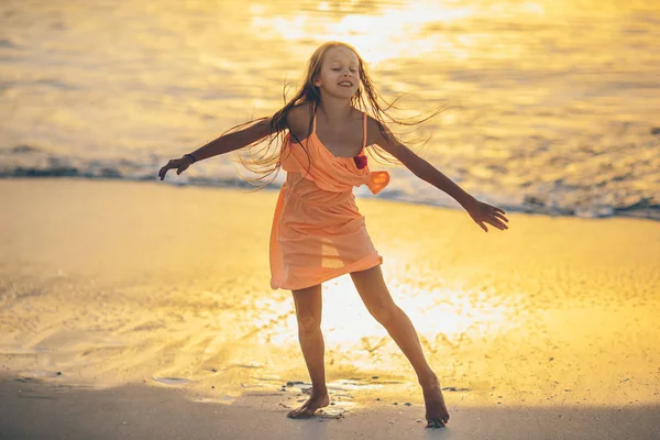 Schattig gelukkig klein meisje op wit strand bij zonsondergang. — Stockfoto