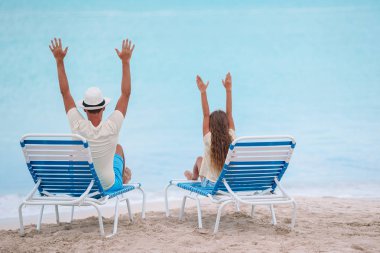 Plajda şezlong üzerinde oturan baba ve kız Eller yukarı