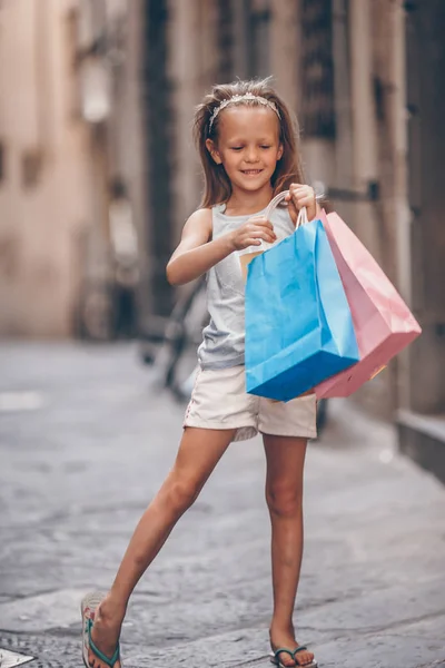 Retrato de niña adorable caminando con bolsas de compras al aire libre en la ciudad europea . — Foto de Stock