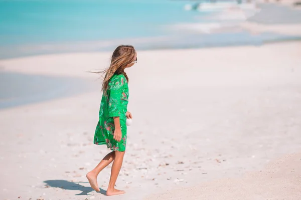 Menina bonito pouco com concha nas mãos na praia tropical . — Fotografia de Stock