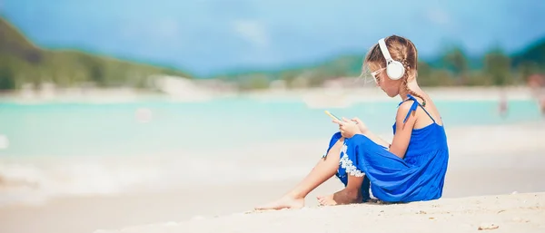 Klein schattig meisje luisteren muziek achtergrond zee — Stockfoto