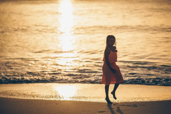 Schattig gelukkig klein meisje op wit strand bij zonsondergang. — Stockfoto