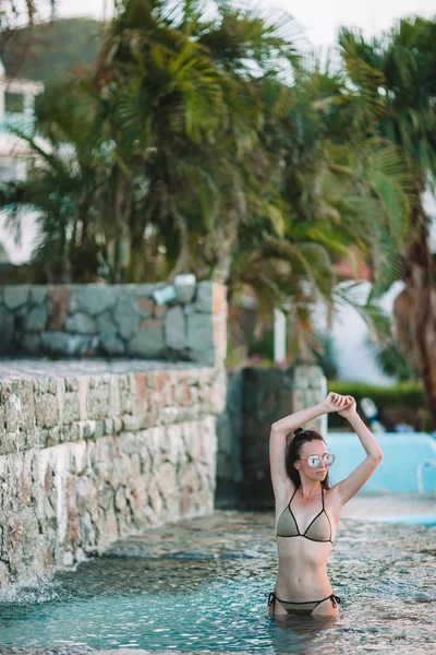 Jovem mulher sexy desfrutando de descanso na borda da piscina exterior — Fotografia de Stock