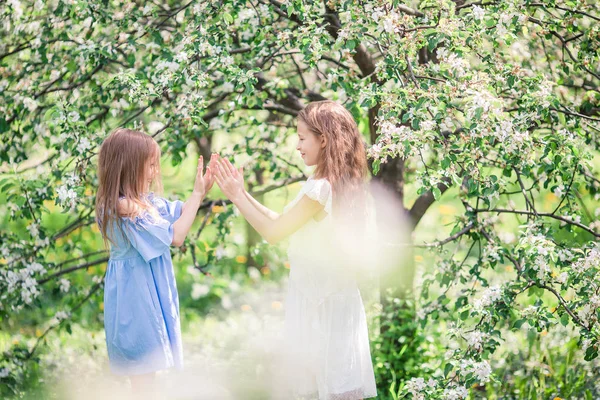 Imádnivaló kislányok a virágzó almafakertben tavasszal — Stock Fotó